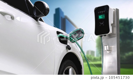 Electric car plugged in with charging station to recharge battery. Peruse 105451730