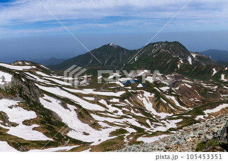 雪残る夏の立山登山 雄山山頂から室堂と大日岳を臨む 105453351