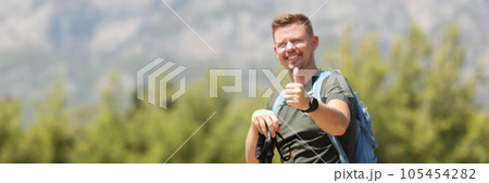 Happy hiker with backpack showing thumbs up against background of mountains on sunny day. Happy hiker with backpack showing thumbs up against background of mountains on sunny day. 105454282