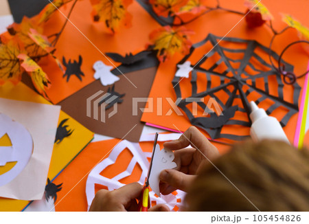 Close-up of children's hands that create paper crafts for Halloween. Homemade decorations for the holiday. 105454826