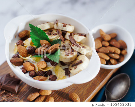 Almond banana salad with chocolate and milk in white plate. Healthy nutritious breakfast. Top view 105455033