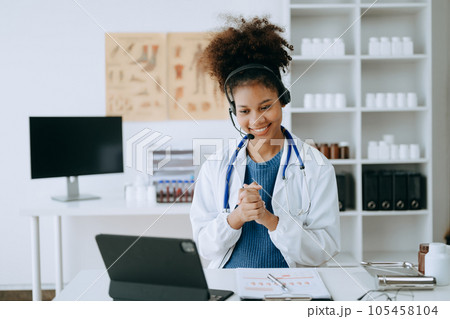 Attractive African female doctor talking while explaining medical treatment to patient through a video call with laptop in office or laboratory Attractive African female doctor talking while explaining medical treatment to patient through a video call with laptop in office or laboratory 105458104