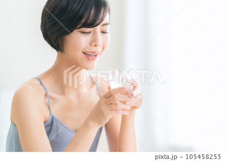 リビングでミネラルウォーターを飲む若い女性 リビングでミネラルウォーターを飲む若い女性 105458255