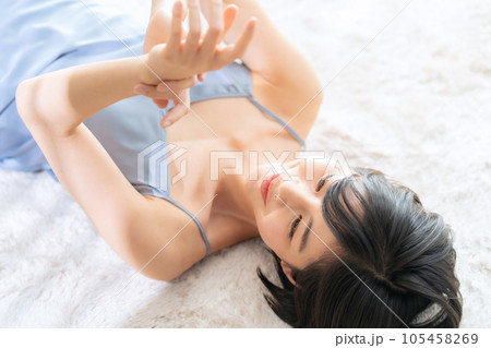 寝転んでスキンケアをする若い女性 寝転んでスキンケアをする若い女性 105458269