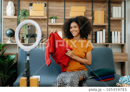 Fashion blogger concept, Young African women selling clothes on video streaming.Startup small business SME, using smartphone or tablet taking receive and checking.. Fashion blogger concept, Young African women selling clothes on video streaming.Startup small business SME, using smartphone or tablet taking receive and checking.. 105459783