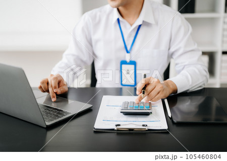Men counting coins on calculator taking from the piggy bank. hand holding pen working on calculator to calculate on desk about cost at office. 105460804