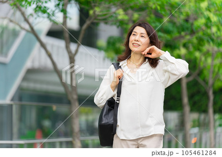 髪をかきあげながらオフィス街を歩くアラフィフのビジネスウーマン 105461284