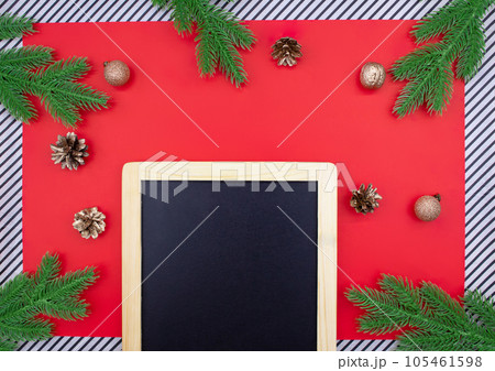 Black chalk board for announcement with spruce branches, golden cones and walnuts, glitter balls on red background and striped. Christmas, New Year flat lay. Copy space Black chalk board for announcement with spruce branches, golden cones and walnuts, glitter balls on red background and striped. Christmas, New Year flat lay. Copy space 105461598