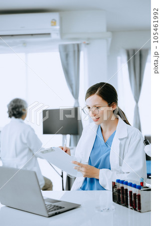Two scientist or medical technician working, having a medical discuss meeting with an Asian senior female scientist supervisor in the laboratory with online reading, test samples and innovation 105461992