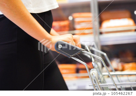 Hands and hips of a young woman with a grocery cart in the grocery section of a supermarket 105462267