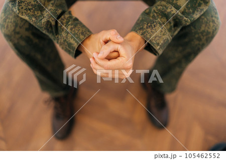Close-up high-angle view of unrecognizable soldier male in camouflage uniform tightly clenching fists sitting in circle during PTSD group therapy session. Concept of mental health, psychotherapy Close-up high-angle view of unrecognizable soldier male in camouflage uniform tightly clenching fists sitting in circle during PTSD group therapy session. Concept of mental health, psychotherapy 105462552