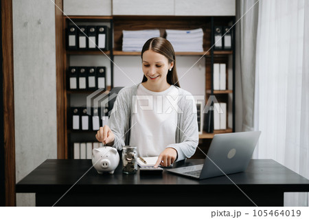 Caucasian Women are putting coins in a piggy bank for a business that grows for profit and saving money for the future. planning for retirement concept in office 105464019