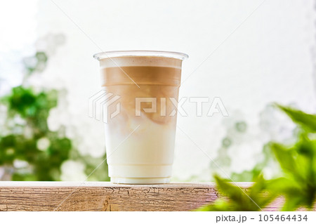 カフェラテ、プラスチックコップに入ったミルクにコーヒーを注ぐ 105464434