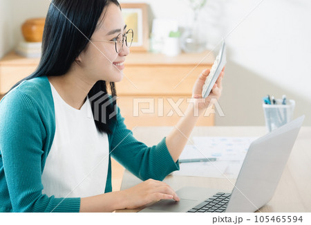 パソコンと電卓で計算する若い女性 105465594