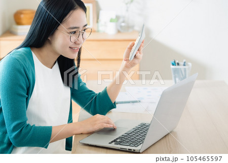 パソコンと電卓で計算する若い女性 パソコンと電卓で計算する若い女性 105465597