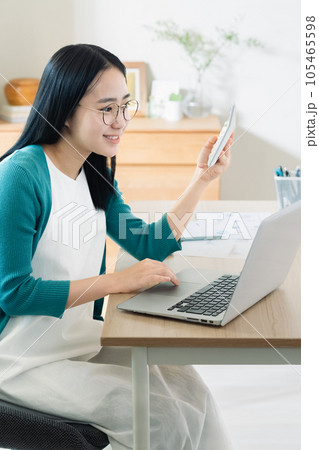 パソコンと電卓で計算する若い女性 105465598