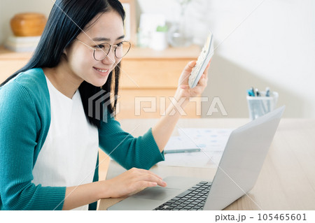 パソコンと電卓で計算する若い女性 105465601