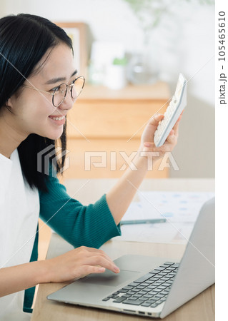 パソコンと電卓で計算する若い女性 パソコンと電卓で計算する若い女性 105465610