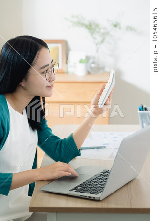 パソコンと電卓で計算する若い女性 パソコンと電卓で計算する若い女性 105465615