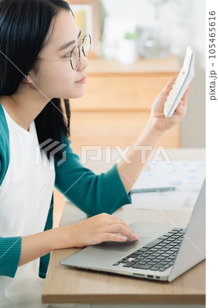 パソコンと電卓で計算する若い女性 パソコンと電卓で計算する若い女性 105465616