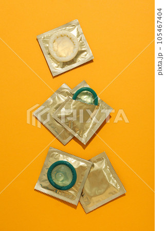 Green condoms on a yellow background close-up 105467404