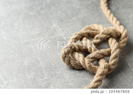 Knotted thick rope close-up on gray background. Place for text Knotted thick rope close-up on gray background. Place for text 105467608