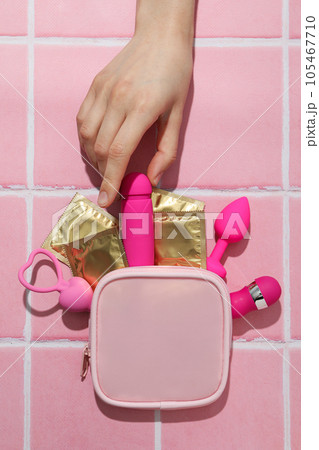 Pink handbag with condoms and sex toys on a pink background 105467710