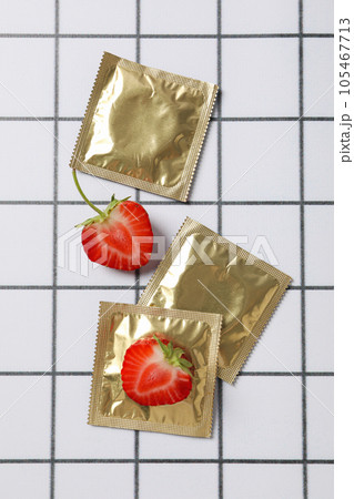 Condoms and strawberries on a light background in a cell 105467713