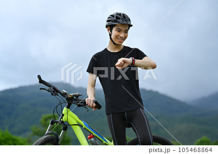 Satisfied man taking break from riding bicycle and checking sport activity progress data on smartwatch Satisfied man taking break from riding bicycle and checking sport activity progress data on smartwatch 105468864