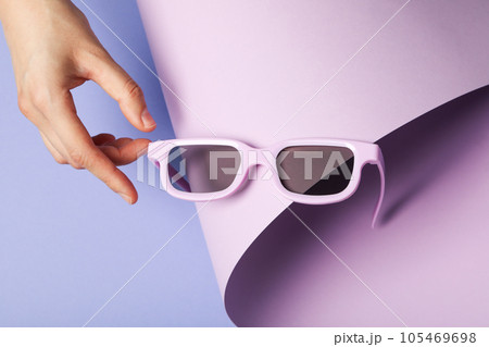 Sunglasses in hand on purple background, close up Sunglasses in hand on purple background, close up 105469698