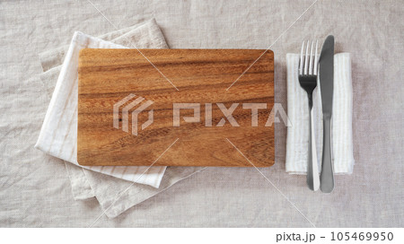Wood plate with fork and knife on napkin on linen tablecloth, top view Wood plate with fork and knife on napkin on linen tablecloth, top view 105469950
