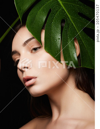 Beauty Portrait of brunette girl in palm leaves. Beautiful young woman with Make-up 105470137
