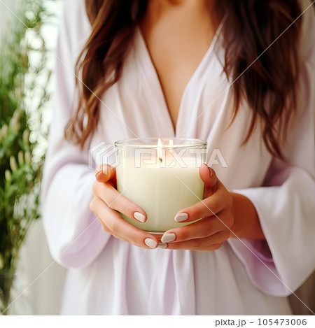 Young woman holding burning candle jar in her hands, container candle mockup closeup shot, mindfulness home interior with green plants Young woman holding burning candle jar in her hands, container candle mockup closeup shot, mindfulness home interior with green plants 105473006