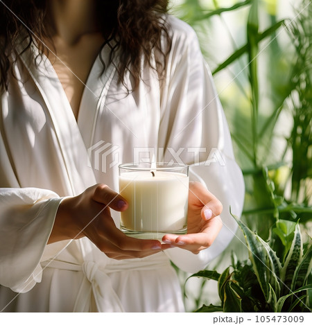 Young woman holding burning candle jar in her hands, container candle mockup closeup shot, mindfulness home interior with green plants Young woman holding burning candle jar in her hands, container candle mockup closeup shot, mindfulness home interior with green plants 105473009