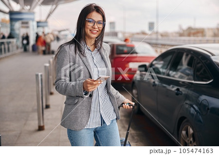 Happy caucasian woman traveller in airport terminal is taking a taxi Happy caucasian woman traveller in airport terminal is taking a taxi 105474163