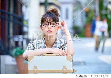 キャリーバックの前で座っている旅先の若い女性 キャリーバックの前で座っている旅先の若い女性 105474329
