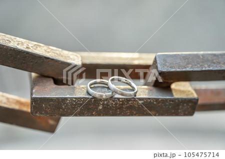 Two hands with wedding rings rest on a strong anchor chain Two hands with wedding rings rest on a strong anchor chain 105475714