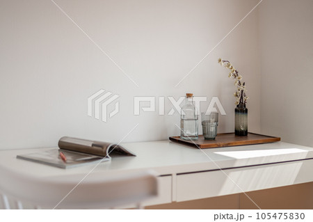 Indoor home office with table, magazine, glass, decorative plant, and water bottle 105475830