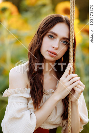 Woman in a dress in a field of sunflowers on a swing 105475879