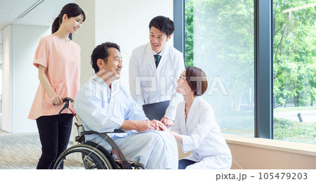 車椅子に乗った男性の患者と話をする医師 車椅子に乗った男性の患者と話をする医師 105479203