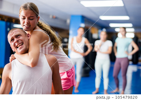 Girl practicing guillotine choke on opponent in sparring with man Girl practicing guillotine choke on opponent in sparring with man 105479820