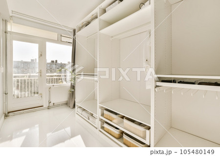 the inside of a room with white walls and shelves on each side, there is an open door that leads to a balcony the inside of a room with white walls and shelves on each side, there is an open door that leads to a balcony 105480149