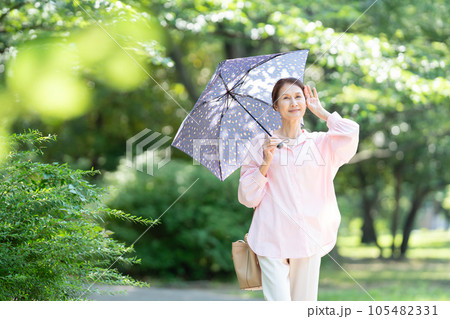 日傘を刺して歩くシニアの女性 日傘を刺して歩くシニアの女性 105482331