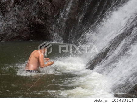 A man bathes in a waterfall. Cold water. Extreme bathing. Nature. A man bathes in a waterfall. Cold water. Extreme bathing. Nature. 105483114