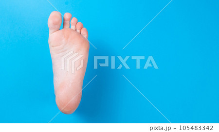 Female bare foot on a blue background. Female bare foot on a blue background. 105483342