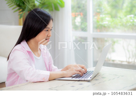 Beautiful young asian woman typing keyboard on laptop computer on desk at home. Beautiful young asian woman typing keyboard on laptop computer on desk at home. 105483631