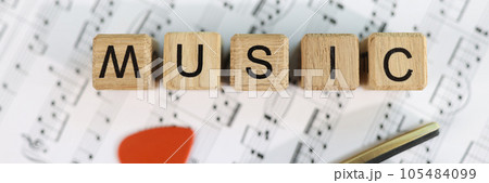 Wooden cubes with letters music and guitar pick on musical notes. 105484099