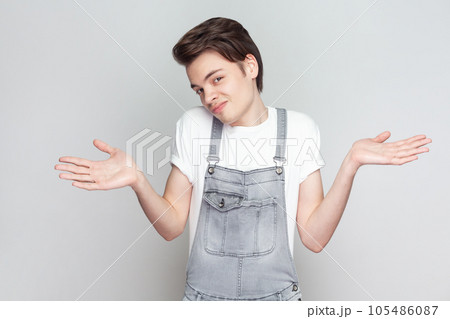 I do not know. Unaware perplexed man spreads palms sideways, has no idea what to do, looks at camera, thinks how to act in troublesome situation. Indoor studio shot isolated on gray background. 105486087