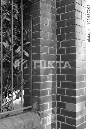 レンガ壁に鉄製フェンスの外壁モノクロ 105487208