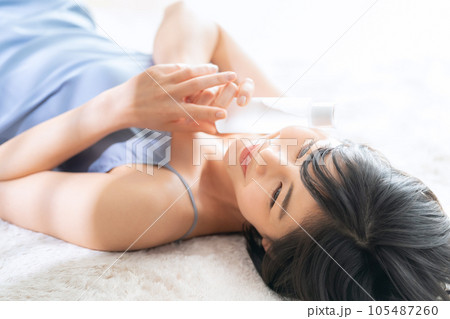 寝転んでスキンケアをする若い女性 寝転んでスキンケアをする若い女性 105487260